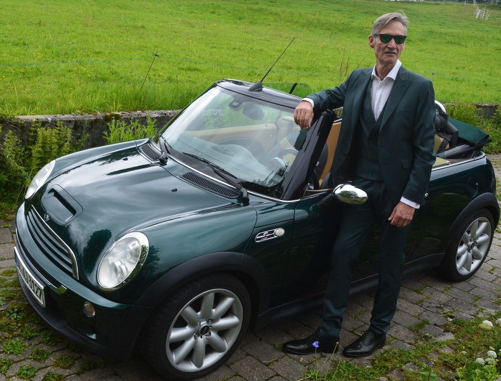 Herr im grünen Anzug an einem Cabrio