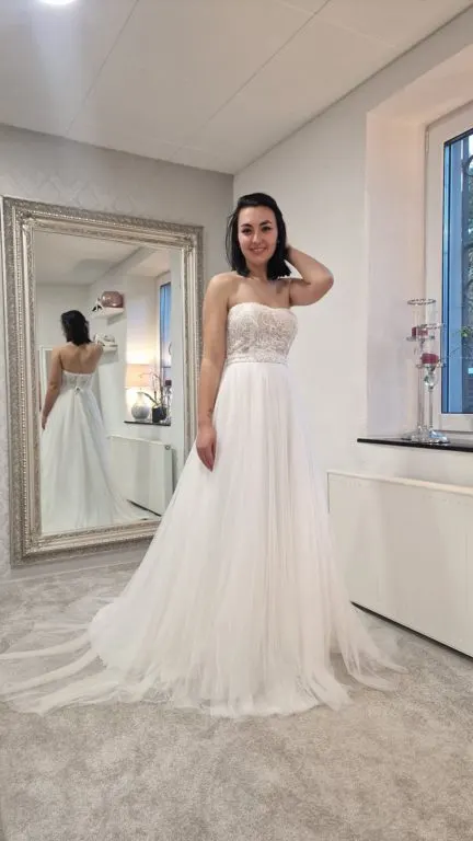 Brautkleid mit Spitzenoberteil vor dem Spiegel